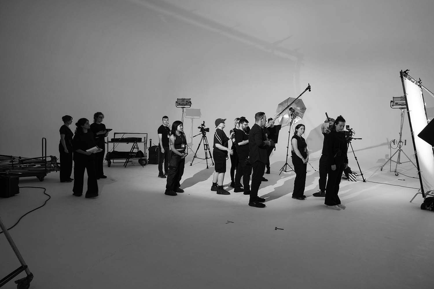 A group of people stand inside a photography studio, surrounded by cameras, tripods, and lighting equipment.