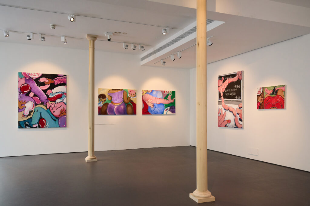A contemporary art gallery with white walls displays five colorful abstract paintings featuring swirling shapes and bold, vibrant colors. Two wooden columns stand in the spacious room.