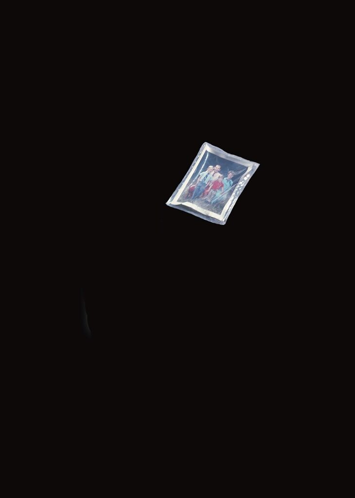 A small photograph of several people standing together is set against a completely black background, making the photo the only visible object in the image.