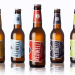 marketing design featuers redwell five beer bottles aligned with the center brought forward and a slight reflection in the floor and different colour labels for each flavour
