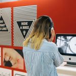 Image of someone looking at a computer screen surrounded by graphic posters