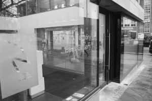 black and white photo of NUA East Coast Gallery exterior showing tall glass windows with a glass doorway and a transfer reading Ideas Factory East Gallery