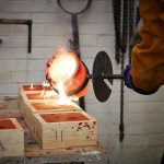 Image of a man pouring hot metal into clay forms