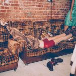 Image of a woman laying on a sofa in a 70 styled studio room