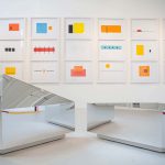 Image of hanging prints in front of mirrored sculptures