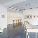 Image of a vitrine and hanging frames pictures in an interior white gallery space