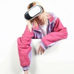 Woman wearing a VR headset with her arm hanging over a white wall