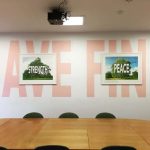 wooden table in white room. big pink words on wall saying