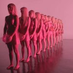 pink light shining on a row of people in dresses holding balloons