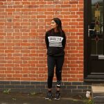 BA Interior Design student Mahisha standing by a brick wall and a front door