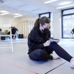 An acting student sits cross legged in the Acting Studio