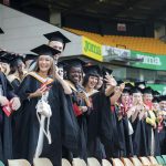 A photo of Norwich University of the Arts graduates smiling and waving at Graduation 2023.