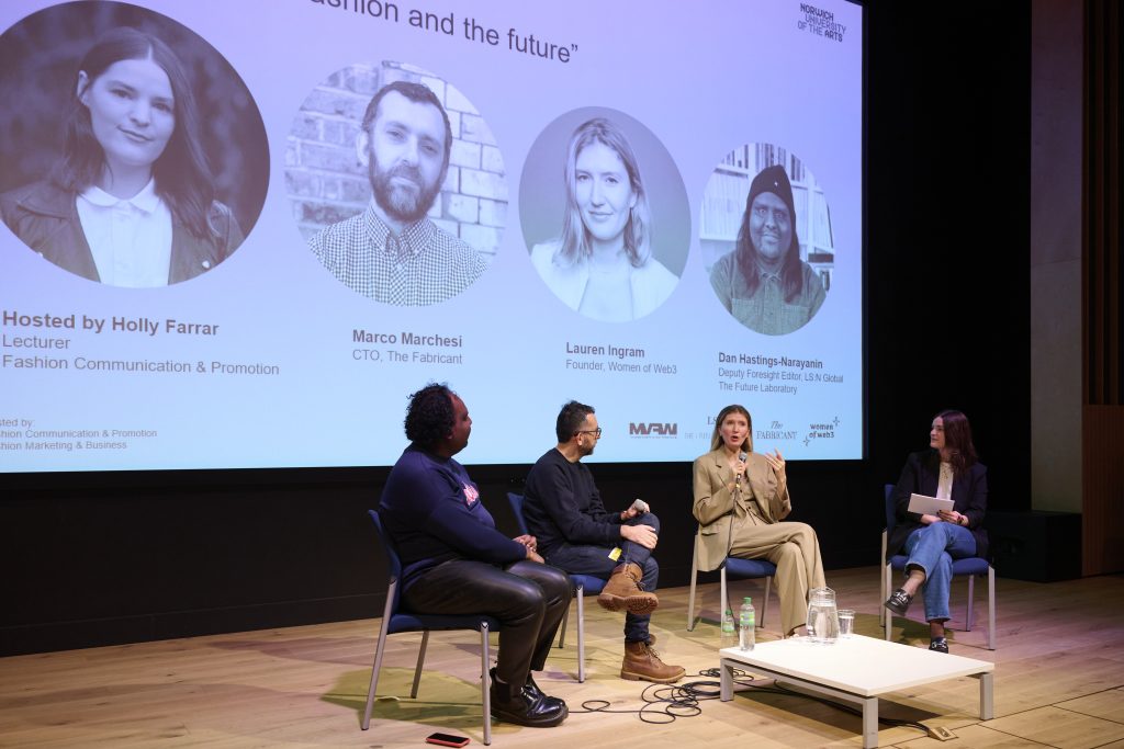 A photo of the panel discussion from the Digital Fashion Symposium at Duke Street Riverside. The image is of four industry professionals sat together talking in-front of a large audience.