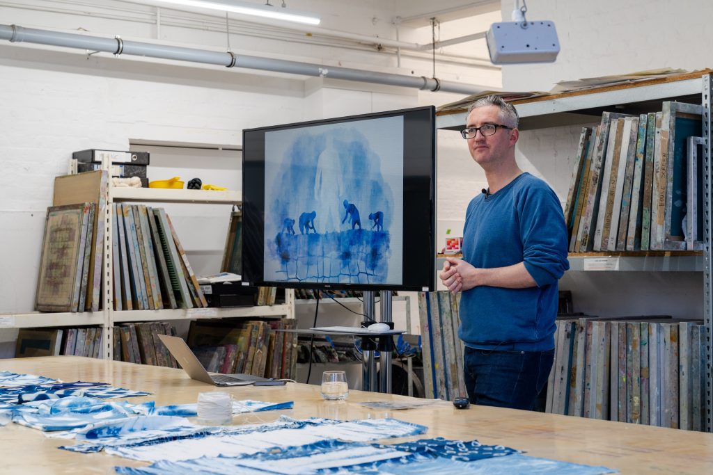 A photo of Ben Musgrave presenting and talking about indigo, fabric dyeing.