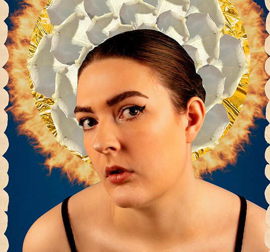 Work by photography student Claudy Woods. Claudy looks at the camera with head turned slightly to one side. There is a grey circular shape behind her head, on a blue background.