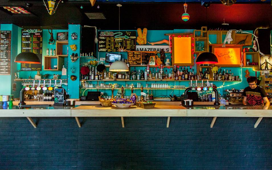 Photograph of Playhouse Bar. A colourful bar with turquoise walls and lots of things in many colours hung behind the bar.
